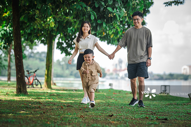 年轻的亚洲家庭在公园里享受追逐游戏图片素材