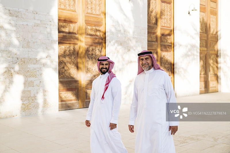 在吉达文化广场，两位快乐的商人穿着沙特传统长袍和头巾的肖像图片素材