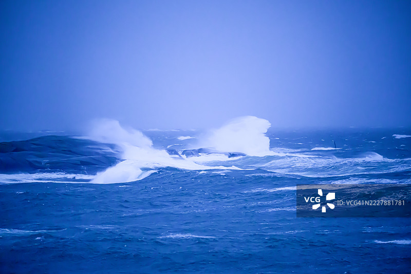 海浪拍打着悬崖，水花四溅，空气中弥漫着水汽，岩石和一切都被水和盐覆盖，变得光滑。图片素材