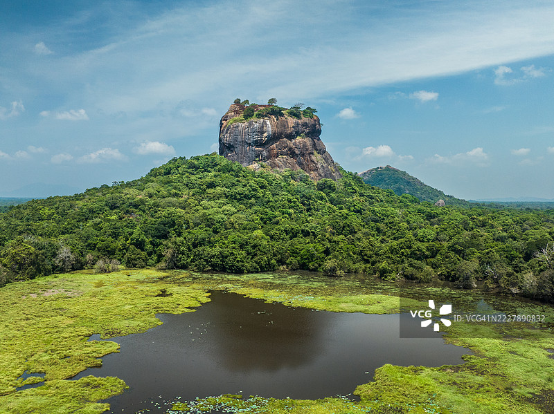 在阳光明媚的日子里，从空中俯瞰覆盖着藻类的湖泊中的狮子岩，斯里兰卡中央省马塔勒区。图片素材