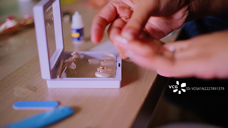 DIY美甲 - 亚洲女性自己粘贴假指甲。图片素材