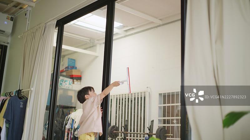 小男孩在帮爸爸擦窗户。4k图片素材