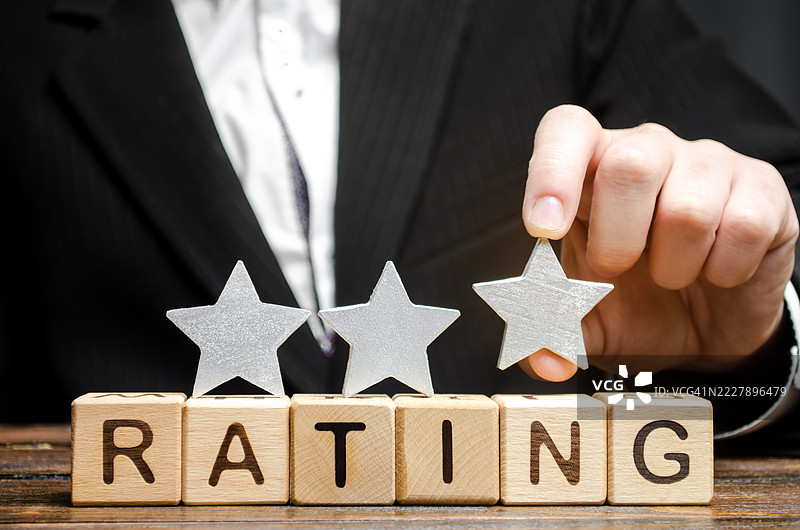 商人将一颗星星放在拼写“Rating”的木块上，乌克兰图片素材