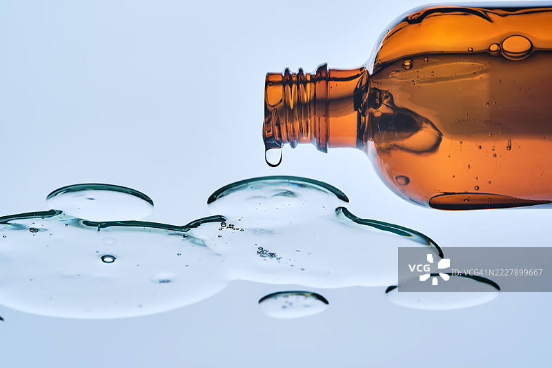 一瓶打开的瓶子，药水从瓶中漏出，底部视角。图片素材