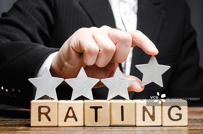 商人将第四颗星放在木块上的“评分”字样上，象征酒店和餐厅的高评分，代表评论家和游客的评价，质量水平四，乌克兰。图片素材