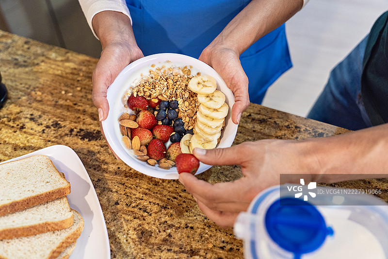 手握着装有水果和燕麦的健康早餐碗。图片素材