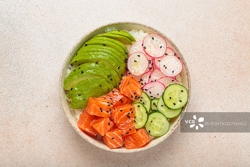 三文鱼饭碗，配牛油果、萝卜、黄瓜和米饭，置于浅色背景上图片素材