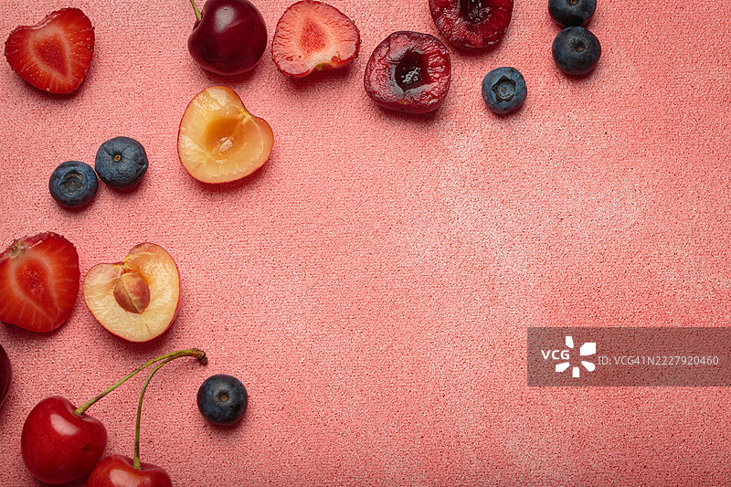 粉色背景上的新鲜水果和浆果俯视图，留有空白区域图片素材