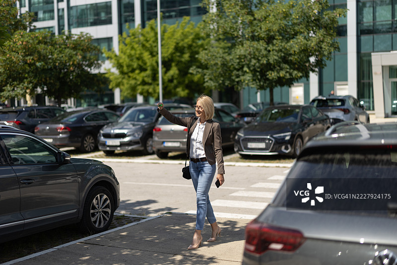 自信的女性在办公楼附近的停车场走动图片素材