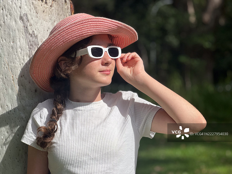 戴着帽子和太阳镜的小女孩仰望天空图片素材