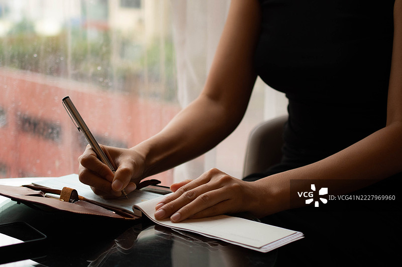 一位中年千禧一代的东南亚女性正在填写一张支票。图片素材