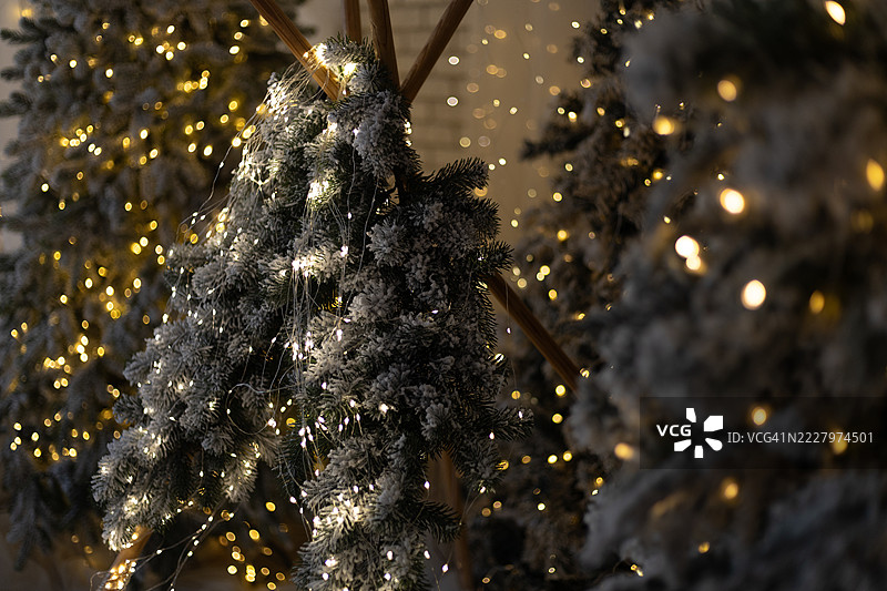 覆盖霜雪的常青树枝装饰着闪烁的灯光，营造出节日的氛围。图片素材