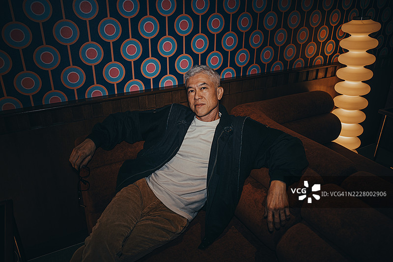 时尚成熟的亚洲男士在复古客厅中放松图片素材