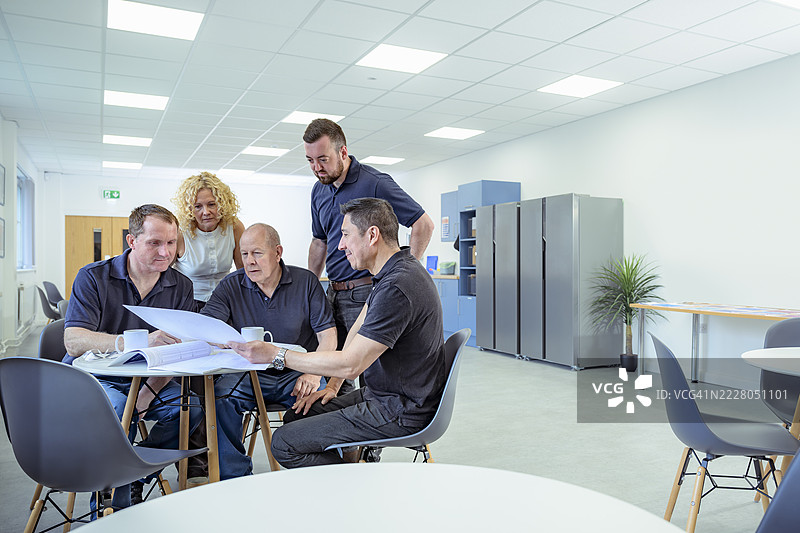 工人在工厂餐厅研究图纸图片素材