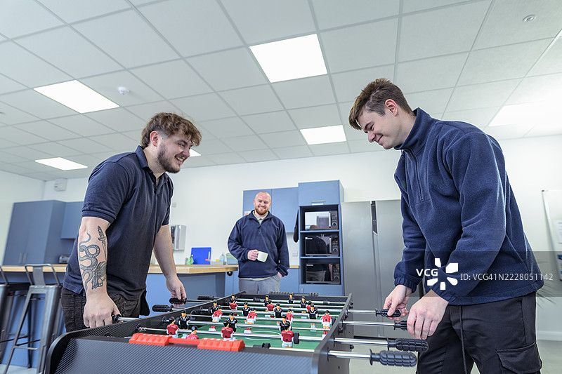 工人在工厂食堂玩桌上足球图片素材