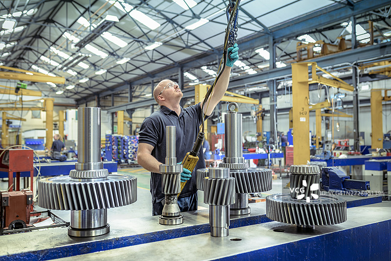 工程师在工程工厂中吊起大型齿轮图片素材