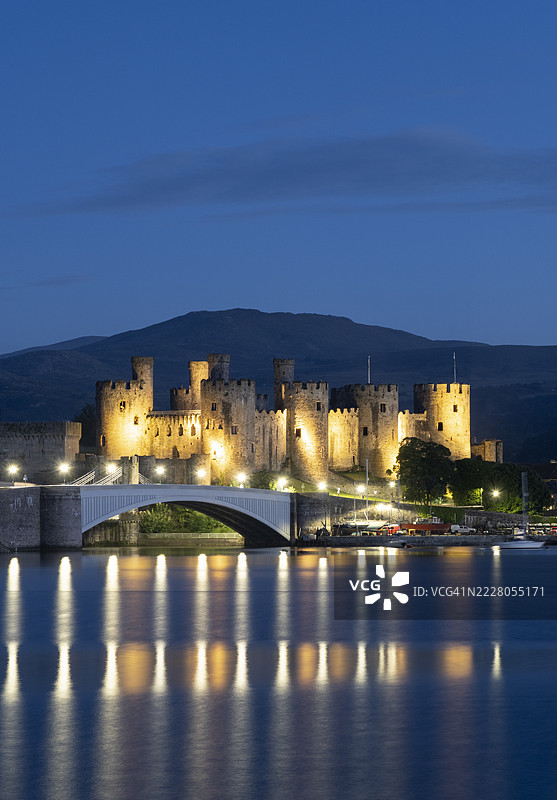 威尔士康威，英国 - 2024年6月6日：夜晚从康威河和康威河口远眺联合国教科文组织世界遗产康威城堡，康威，康威县，北威尔士，英国图片素材