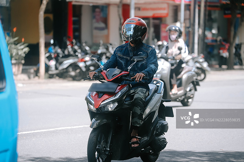 一名穿着牛仔夹克和迷彩裤的男子正在骑滑板车图片素材