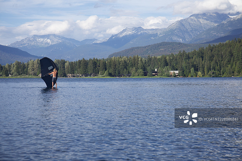 年轻男子在惠斯勒的湖上进行翼帆冲浪图片素材
