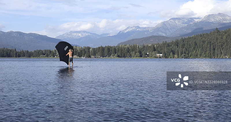 年轻男子在惠斯勒湖上进行翼板运动图片素材