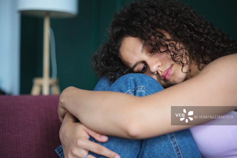 在家感到孤独的伤心Z世代女孩，抱着膝盖。沮丧青少年的肖像。Z世代的孤独感。图片素材