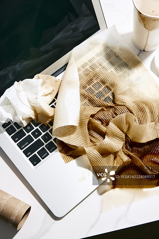 咖啡浸湿的纸巾放在笔记本电脑上图片素材