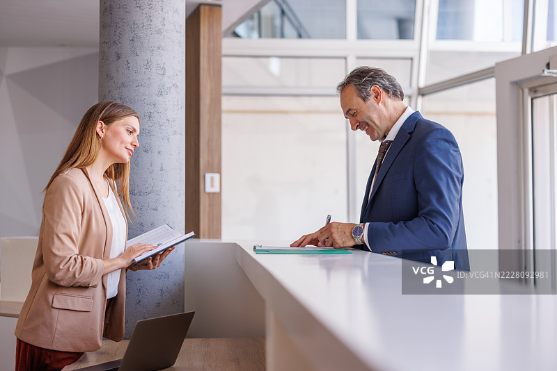 商人在接待处与助理签署文件图片素材