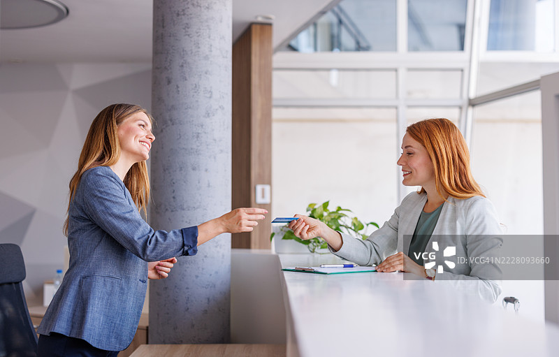女商人在接待处使用非接触式信用卡付款图片素材