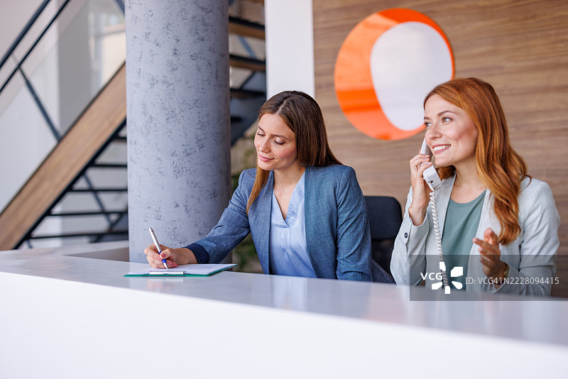 两名接待员在现代办公室的接待台工作图片素材