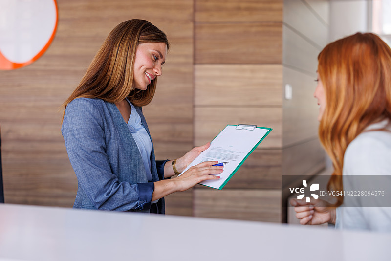 接待员在柜台向客户展示文件图片素材