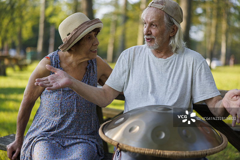 一对年迈的夫妇在户外弹奏手碟鼓，享受音乐爱好，地点在宾夕法尼亚州的波科诺山区。图片素材