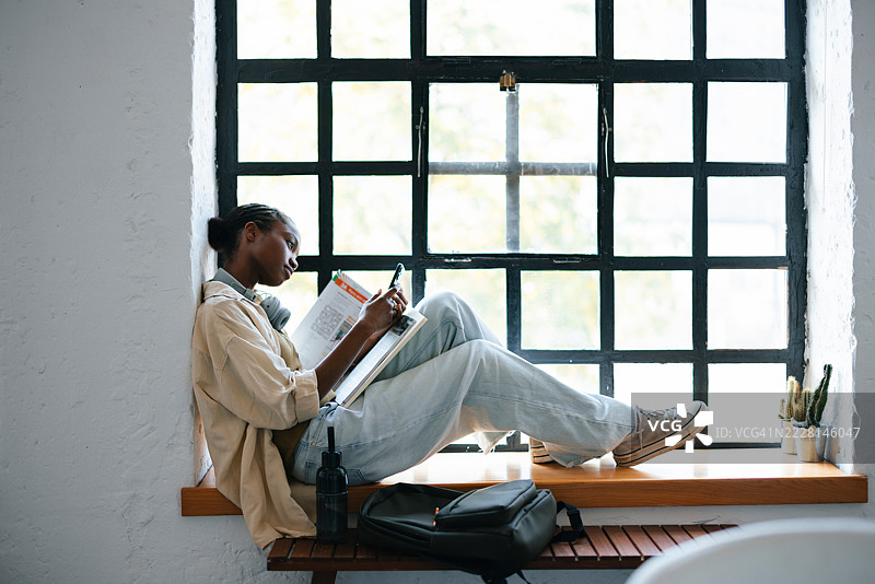 年轻学生在现代学习环境的窗台上阅读图片素材