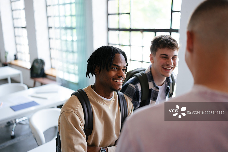 一群朋友在明亮的教室里微笑并互动图片素材