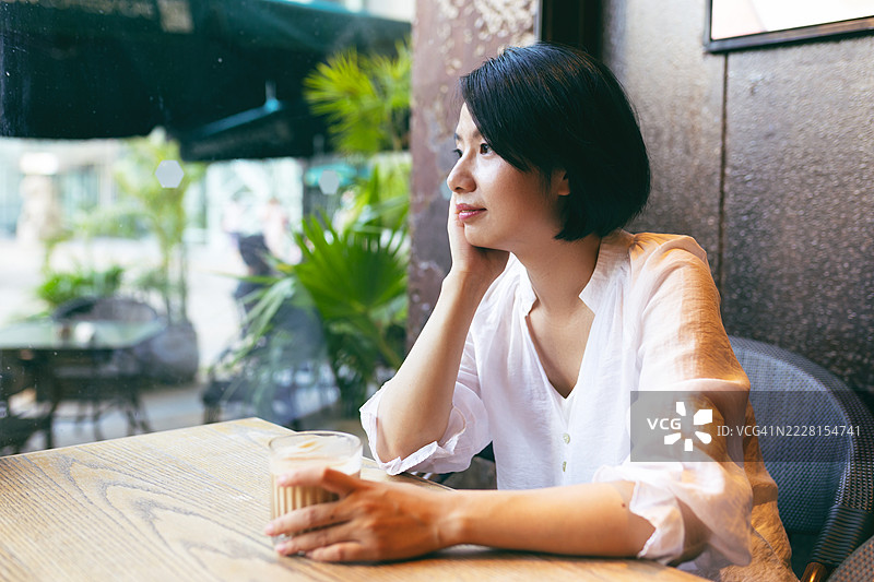 一位亚洲女性在咖啡店里独自享受下午时光图片素材