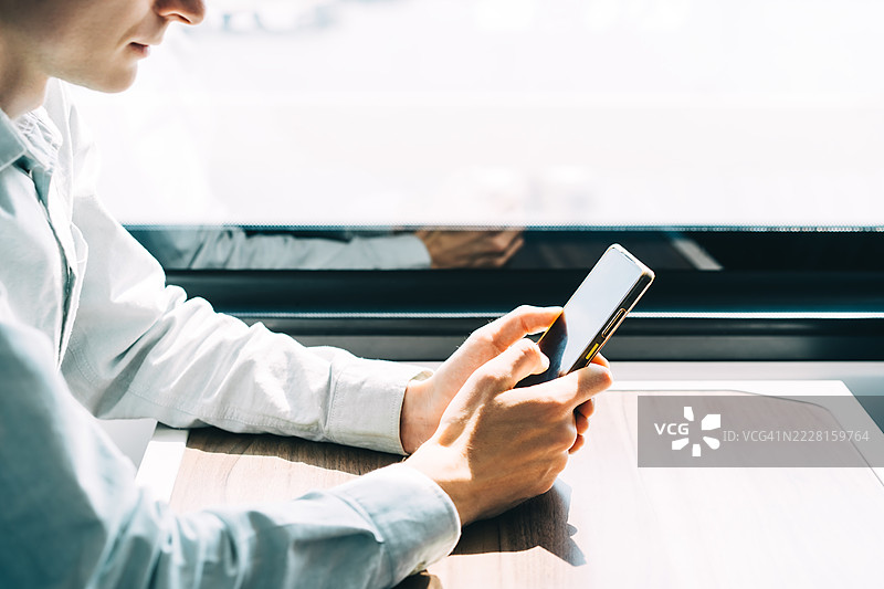 男人在火车上旅行时手持智能手机的特写镜头。图片素材