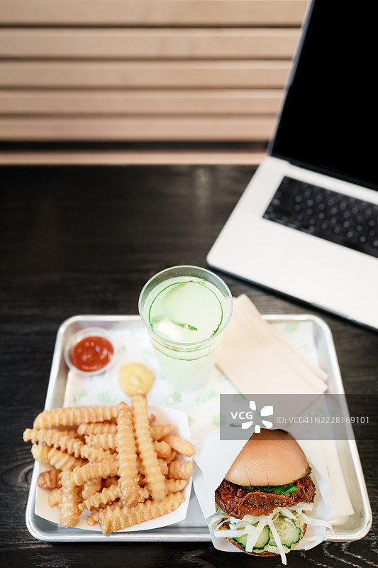 工作桌上的快餐午餐，包括波浪薯条、鸡肉三明治和黄瓜汽水图片素材
