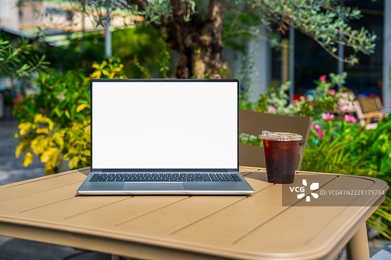 咖啡馆背景下桌子上的笔记本电脑空白屏幕。咖啡店桌子上的笔记本电脑空白屏幕，背景模糊。图片素材