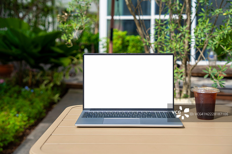 咖啡馆背景下桌子上的笔记本电脑空白屏幕。咖啡店桌子上的笔记本电脑空白屏幕，背景模糊。图片素材