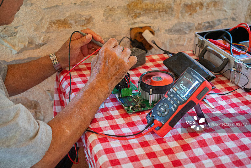 资深电工使用数字万用表检查无人机电池图片素材
