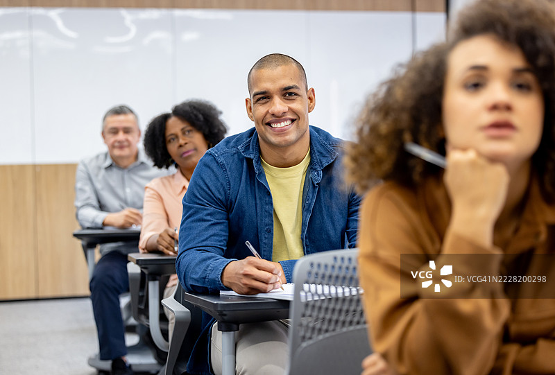 快乐的大学生在课堂上专心听讲图片素材