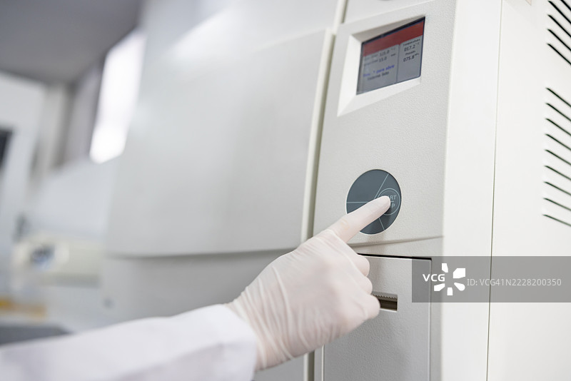 实验室中，科学家特写按下灭菌器上的按钮图片素材