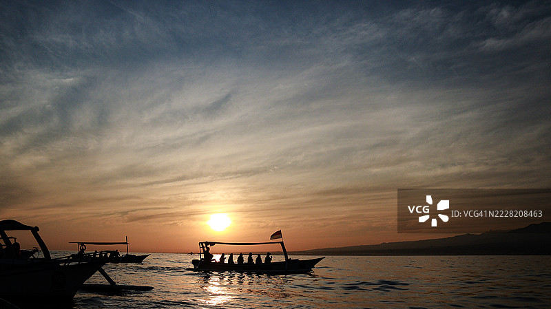 巴厘海上船只的剪影与日出黄昏天空的背景图片素材