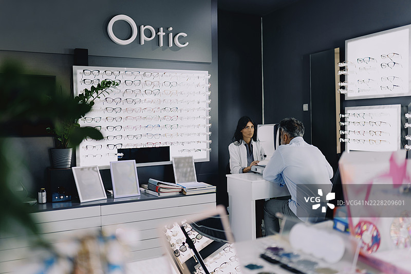 女眼科医生在现代眼科诊所使用诊断设备为老年男性患者进行眼部检查。图片素材