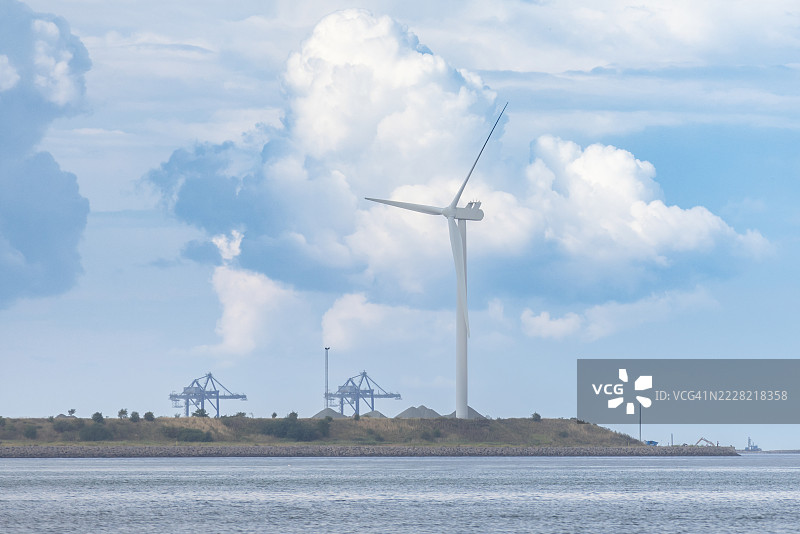 风力发电机与多云的天空背景。图片素材