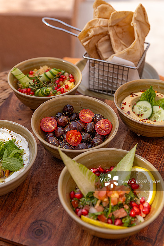 阿拉伯小吃拼盘，包括鹰嘴豆泥、茄子酱、酸奶酱和葡萄叶，适合在户外餐厅享用的中东美食。图片素材