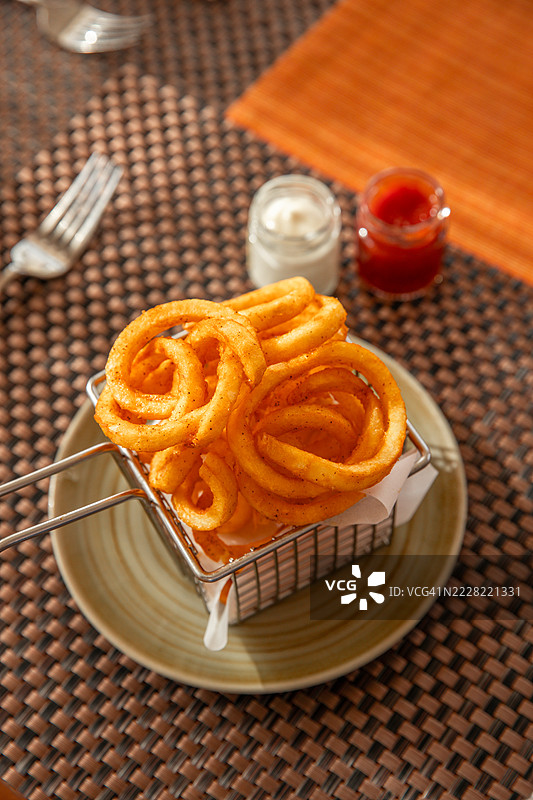 餐厅里提供的卷曲薯条小吃，配有美乃滋和番茄酱图片素材