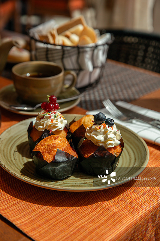 早餐桌上摆放着甜点、纸杯蛋糕和糖霜涂层的松饼图片素材