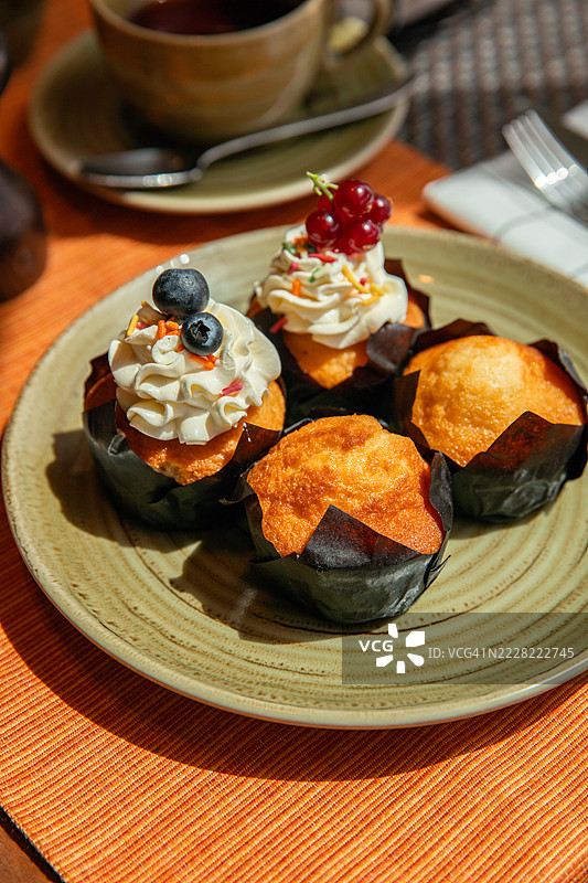 早餐桌上摆放着甜点、纸杯蛋糕和糖霜涂层的松饼图片素材