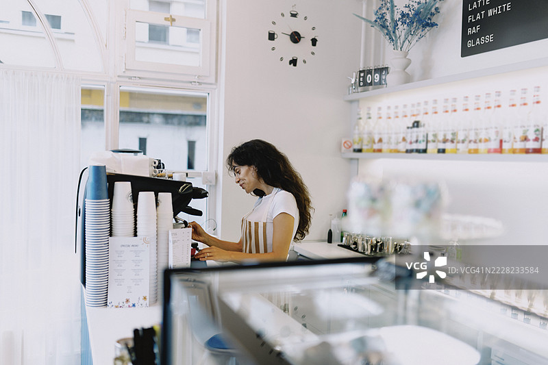 女性咖啡师在小咖啡馆使用意式咖啡机制作咖啡图片素材