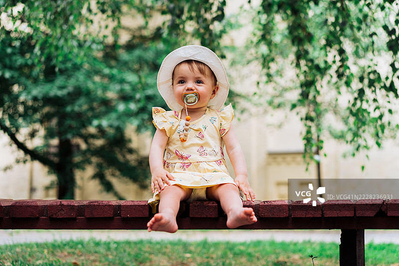 可爱的婴儿戴着帽子，在公园环境中享受户外时光图片素材